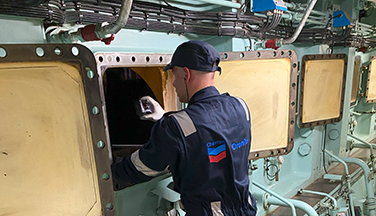 Worker performing engine test on large ship engine.