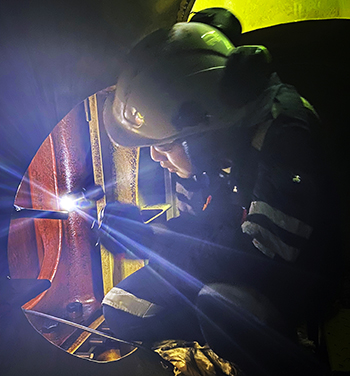 Worker inspecting marine engine during field test.