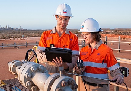 Two workers inspecting pipe at CO₂ injection well.